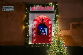 Julpyntat skyltfönster bredvid julgran med julkulor