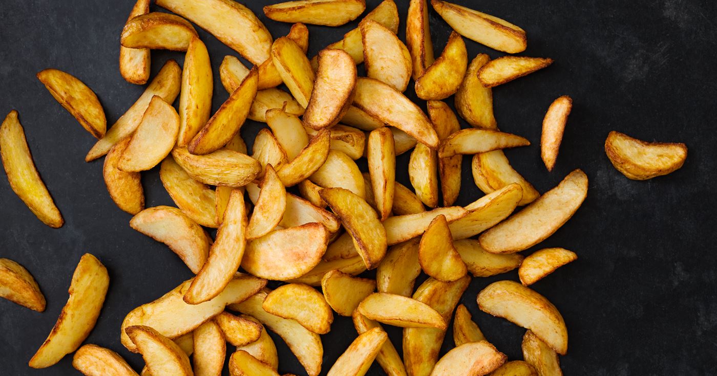 Ugnsstekta potatisklyftor på svart plåt